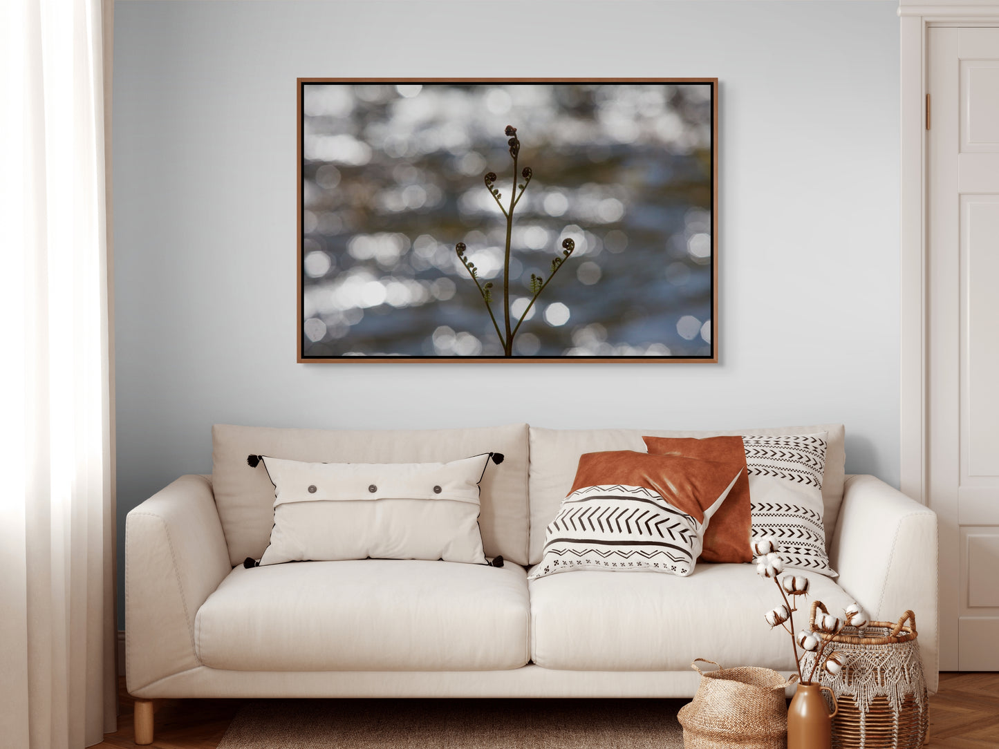 Beige sofa with decorative pillows and a framed artwork depicting a bracken fern sprouting its fronds in spring on the wall. Cedar float frame.