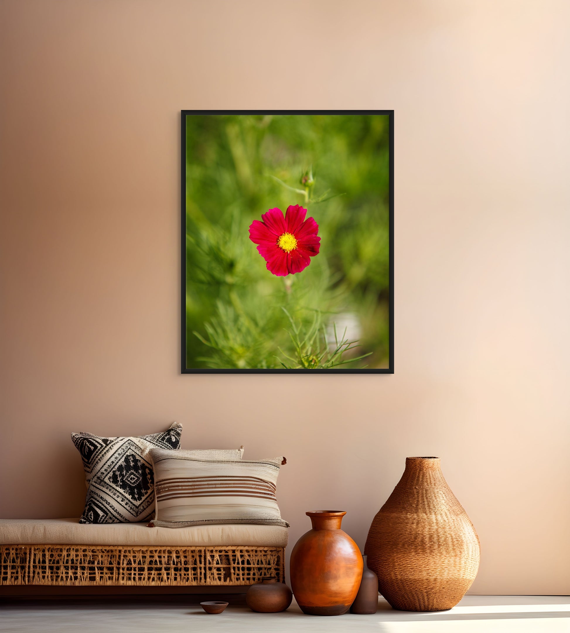 Framed photograph of a red flower on a wall above a sofa with decorative pillows and vases.