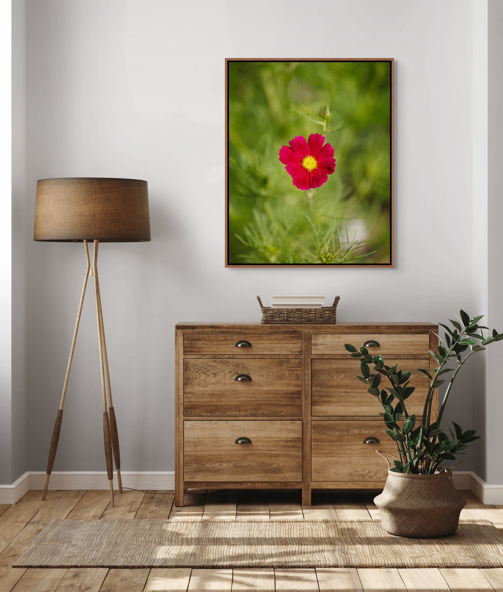 Wooden dresser with a cedar framed fine art photo of a cosmo flower, lamp,  and plant in a room setting