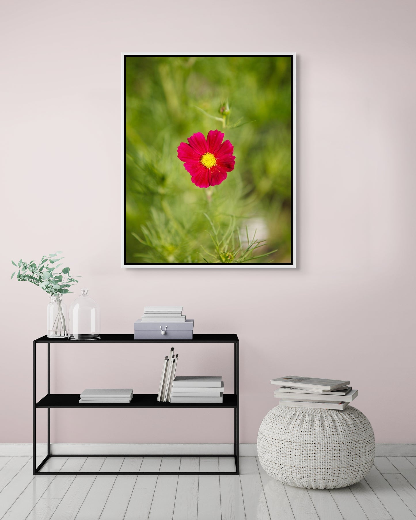 Framed photograph of a pink flower on a wall above a console table.