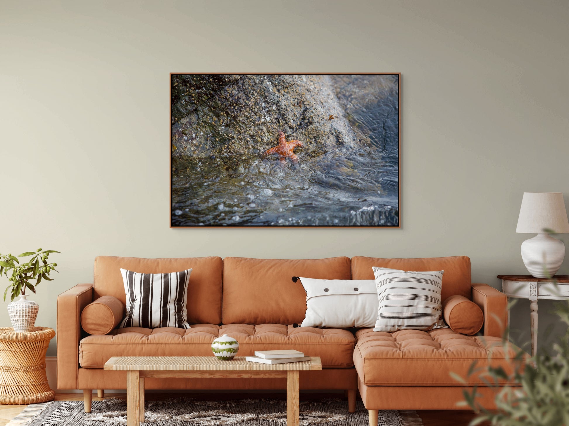 Living room with a orange sofa, coffee table, and decorative pillows, featuring a large cedar framed picture on the wall of a starfish resembling Patrick Star.