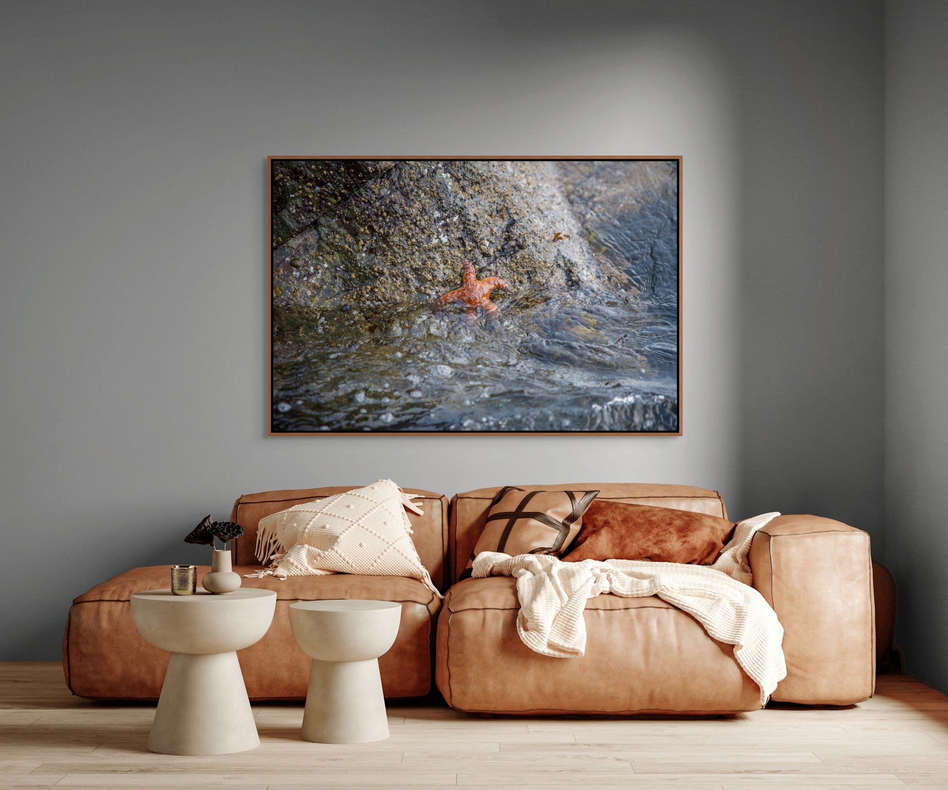 Living room with a brown leather sofa, two white tables, and a large cedar framed art print on the wall of a starfish resembling Patrick Star.