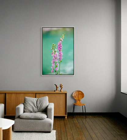 White framed floral artwork on a gray wall above a gray armchair and wooden sideboard.
