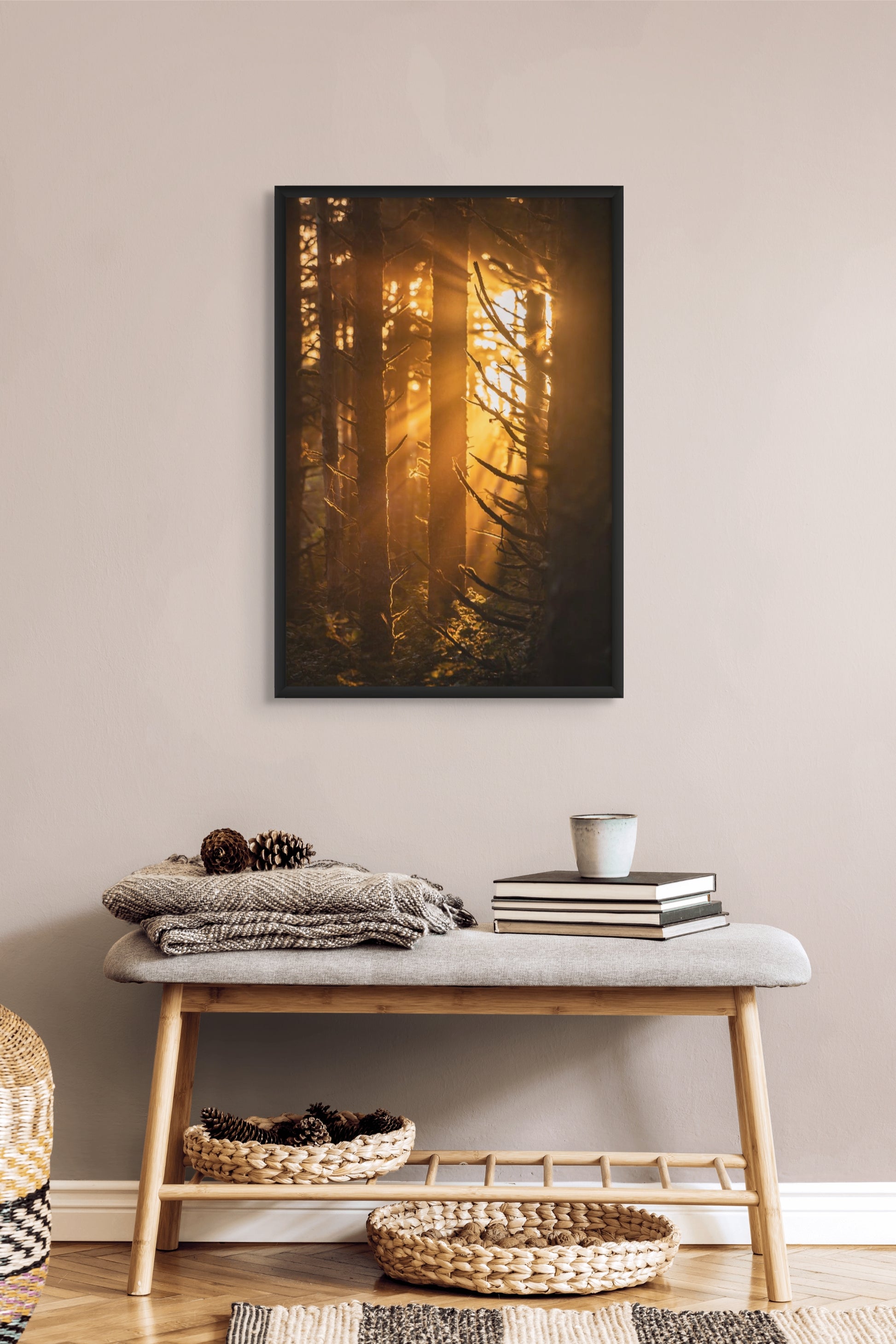 Framed artwork of sunlight filtering through trees in a forest with sun rays above a bench with decor items in a room. Black float frame.