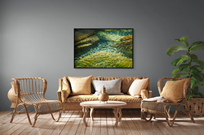 Living room with wicker furniture, a sofa, and a framed nature print on the wall of a crystal clear, glittering, stone-bottom river.